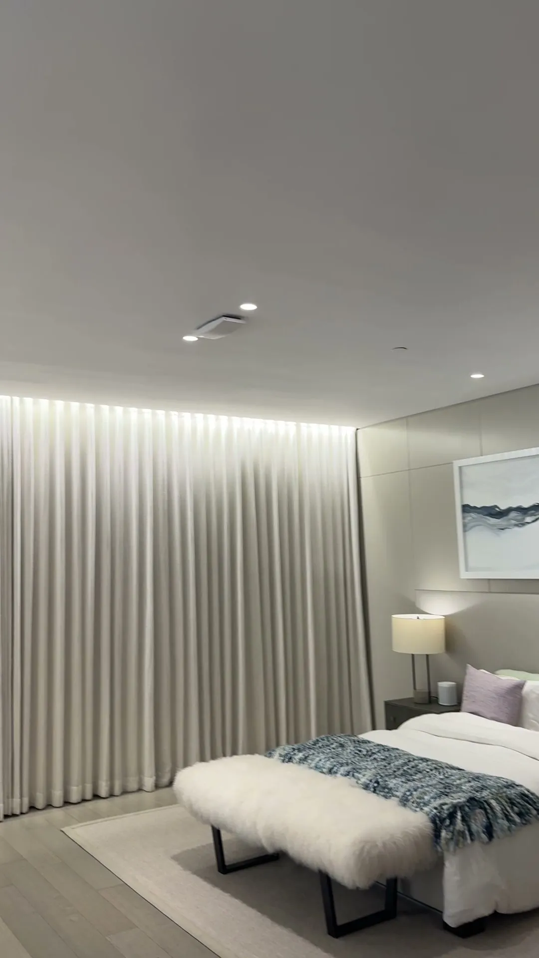 Motorized drapery closed across a bedroom wall with soft cove lighting