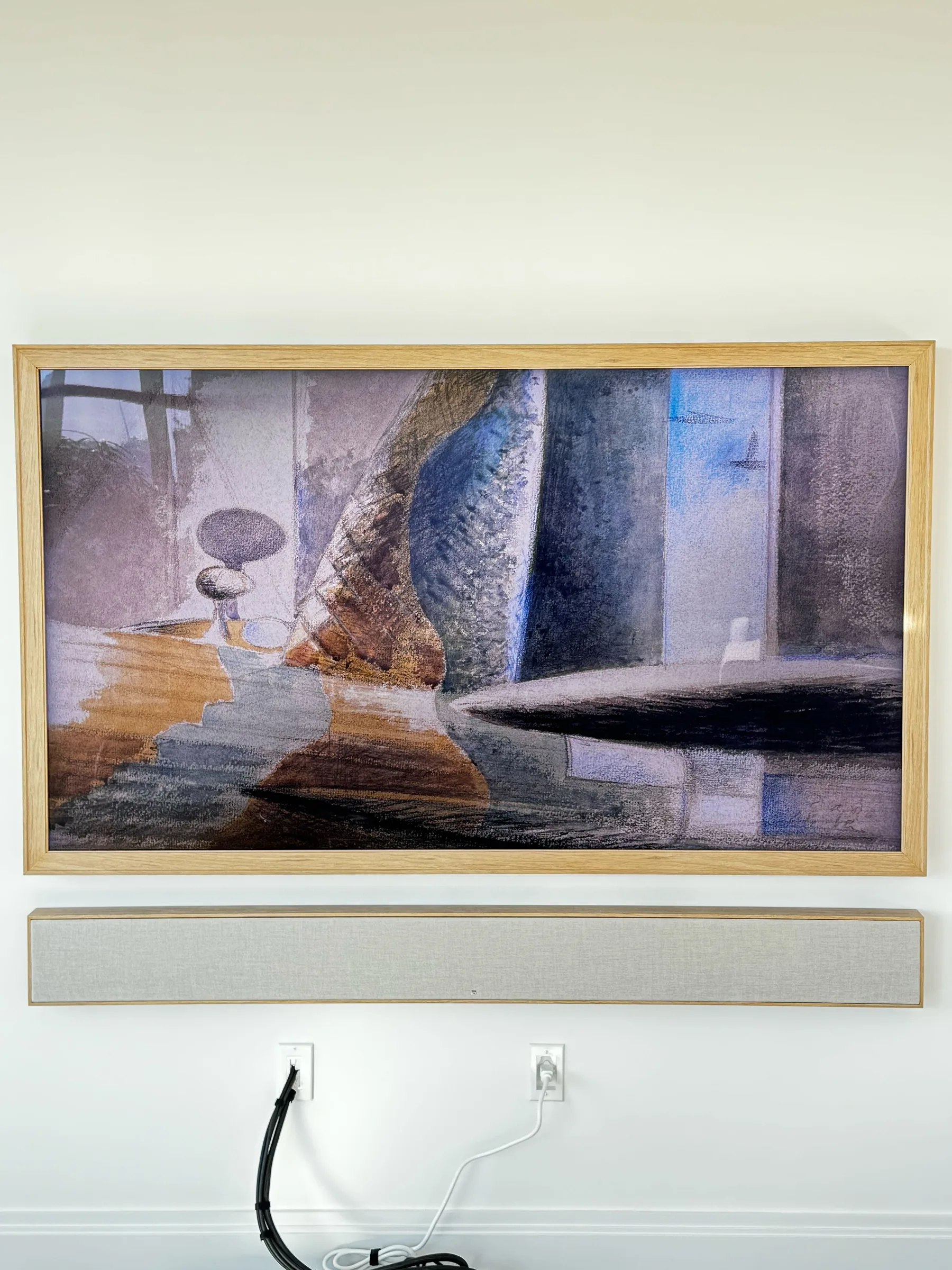 A wood-framed TV in Art Mode displaying an abstract painting, with a fabric-covered soundbar mounted below.