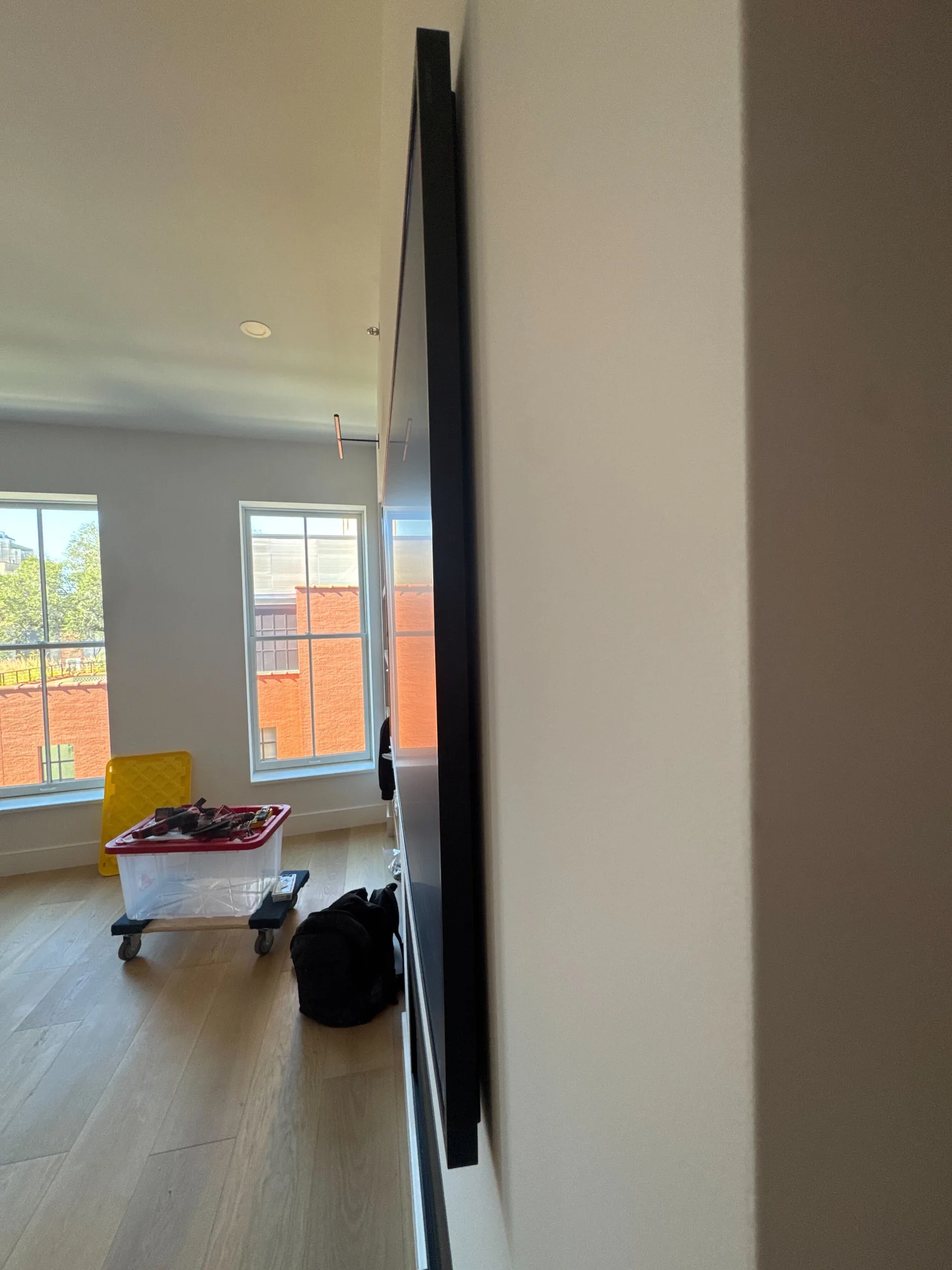 A Frame TV mounted flat on the wall, seen from the side in an empty new-construction room.