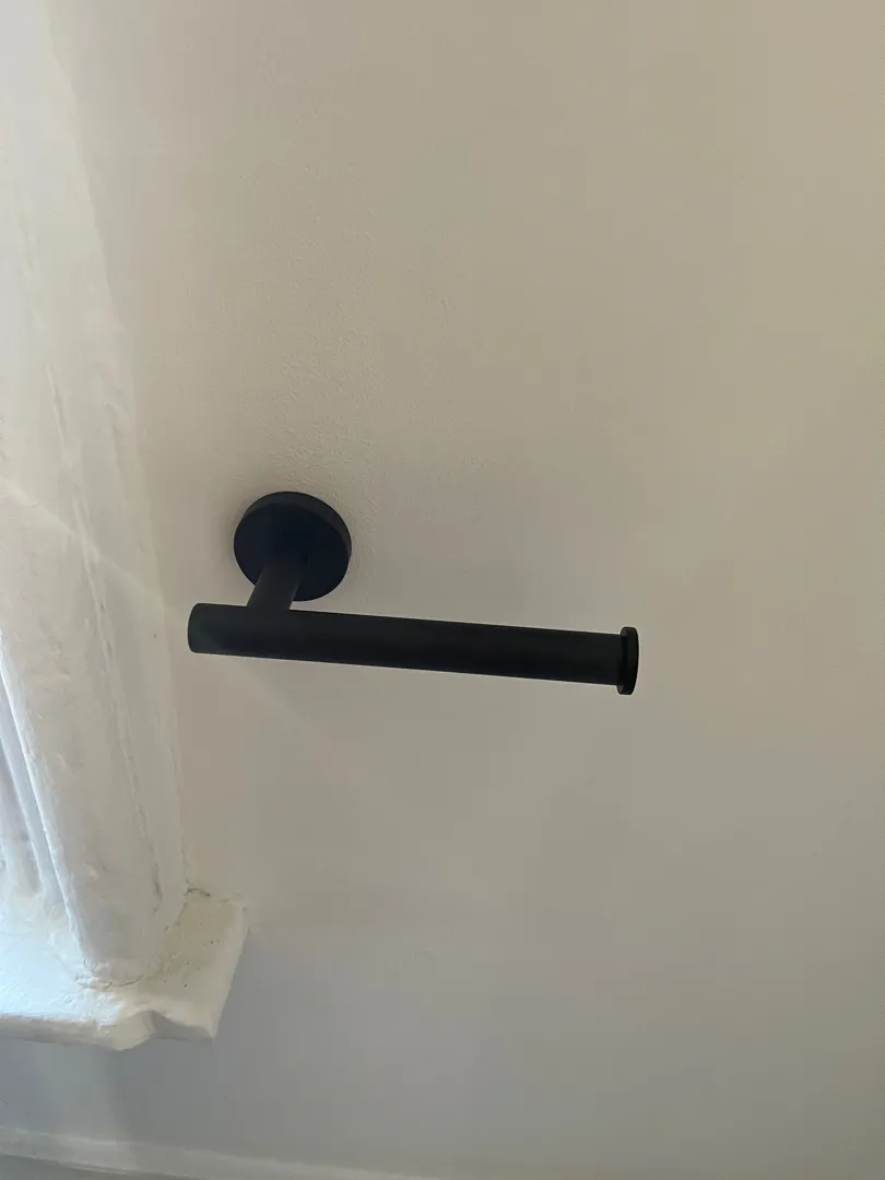A black holder mounted on a white wall near a window.