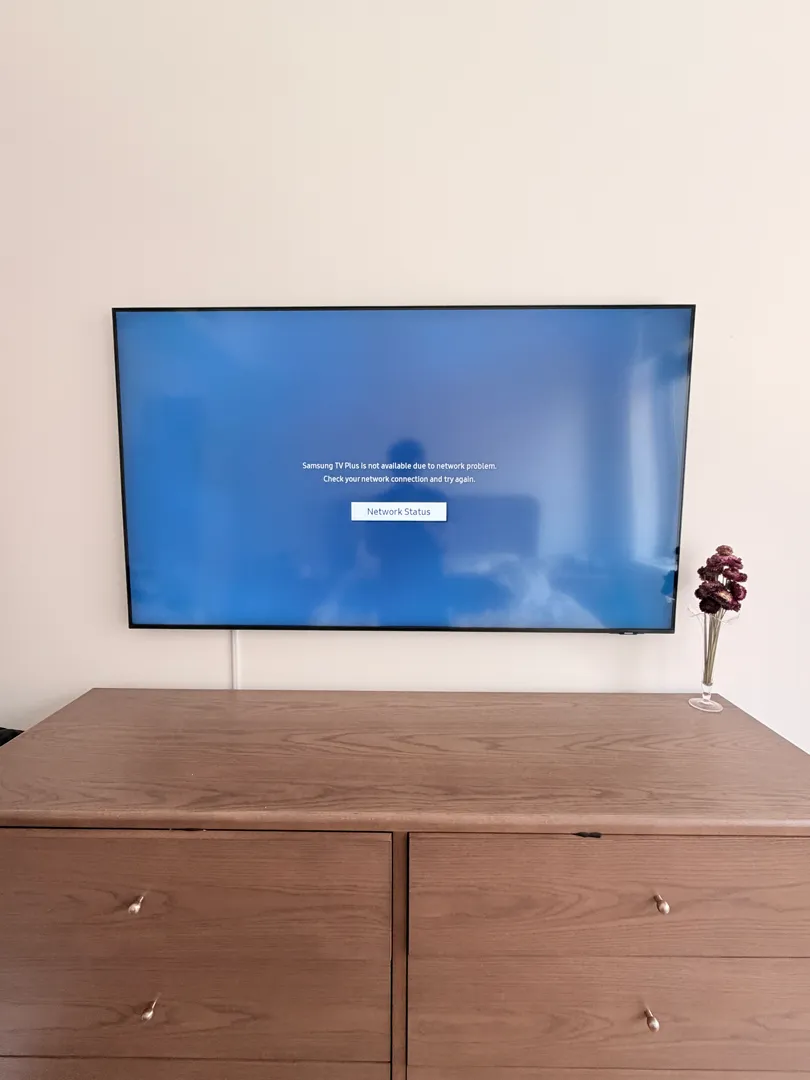 A wall-mounted TV sits above the bedroom dresser.