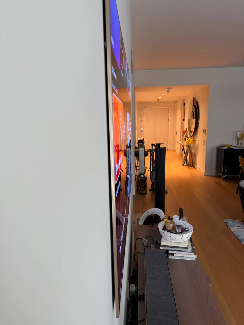 Side view of the 77-inch LG W6 wallpaper TV, sitting flat against the wall above the console.