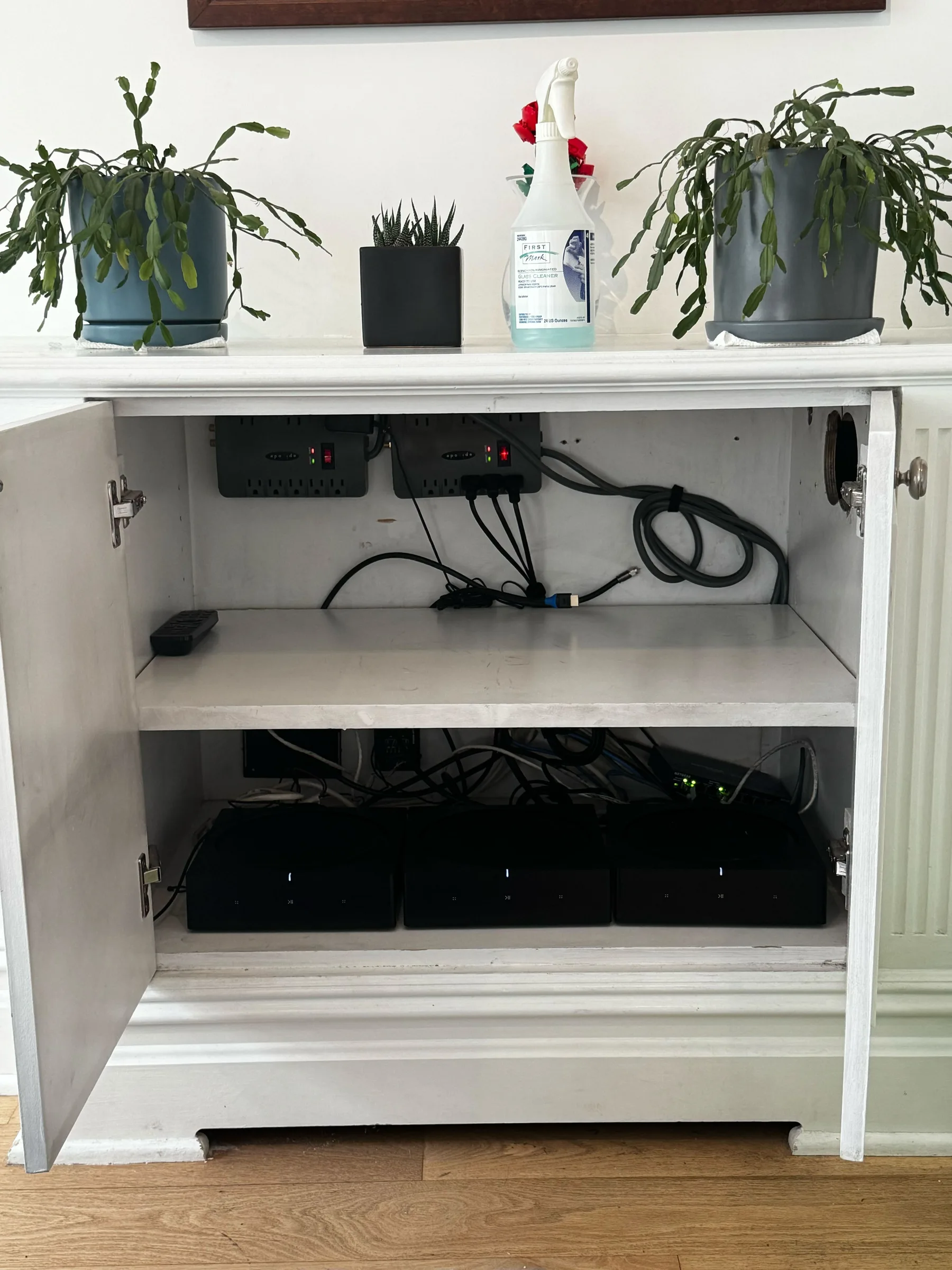 The open cabinet doors reveal power strips and cables neatly organized on two shelves.