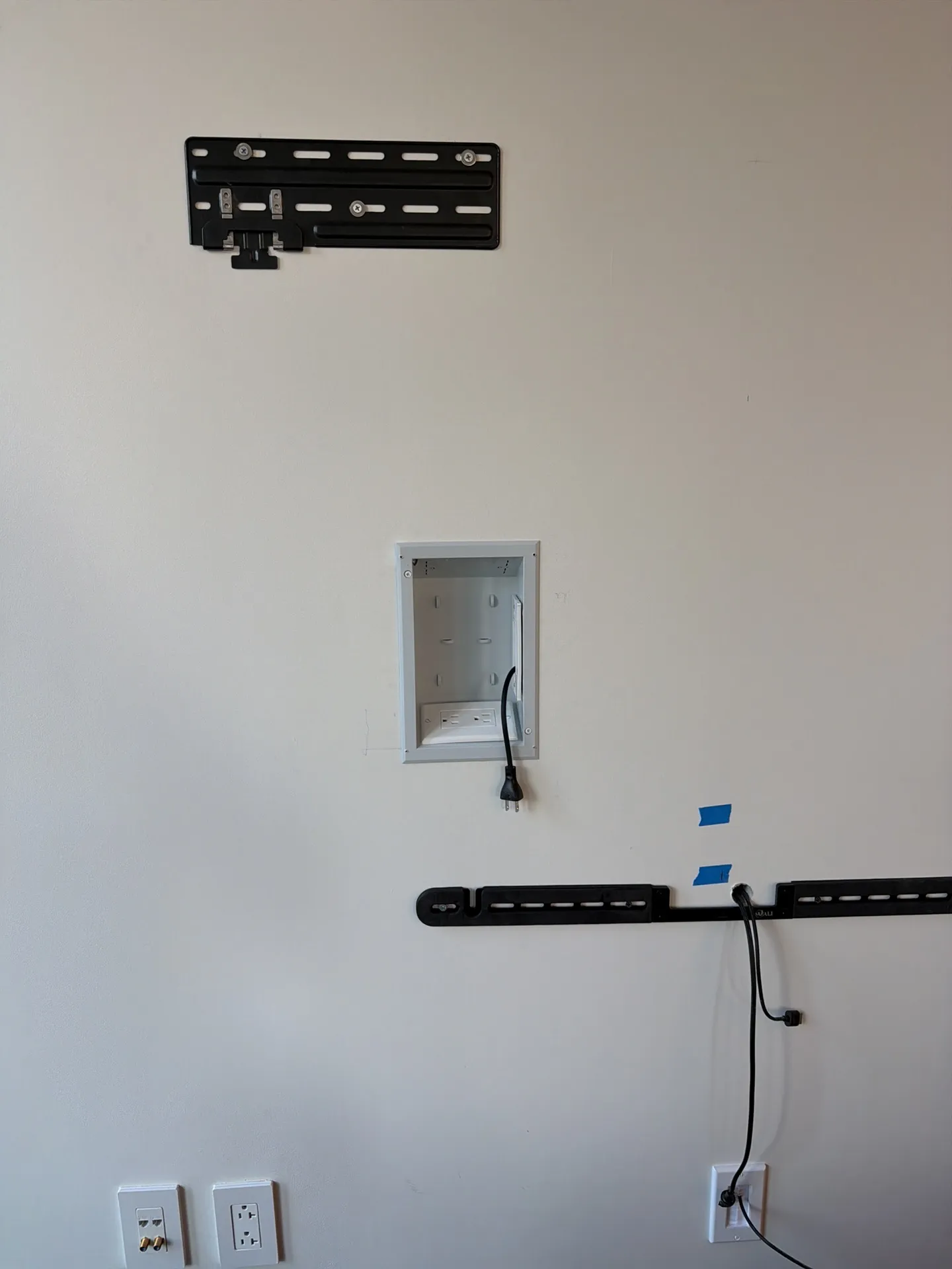 A slim TV wall plate, a new recessed in-wall outlet box and a soundbar bracket fixed to the wall before the TV goes up.
