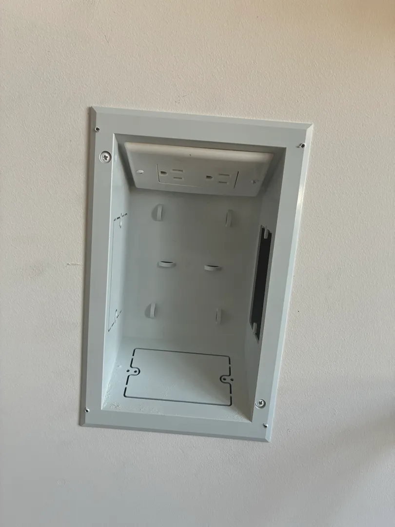 An open recessed in-wall box sits cut into the wall with no cover plate installed yet.
