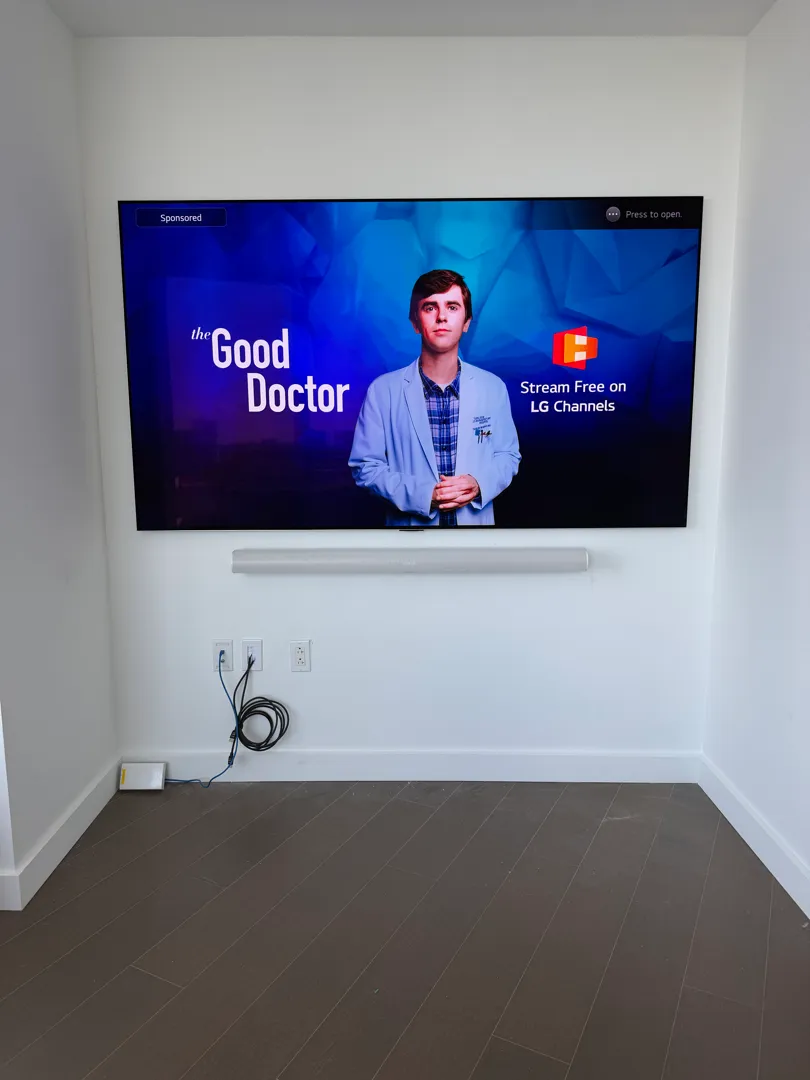 A wide shot of the living room TV in its wall alcove with recessed ceiling lights and a coffee table in the foreground.