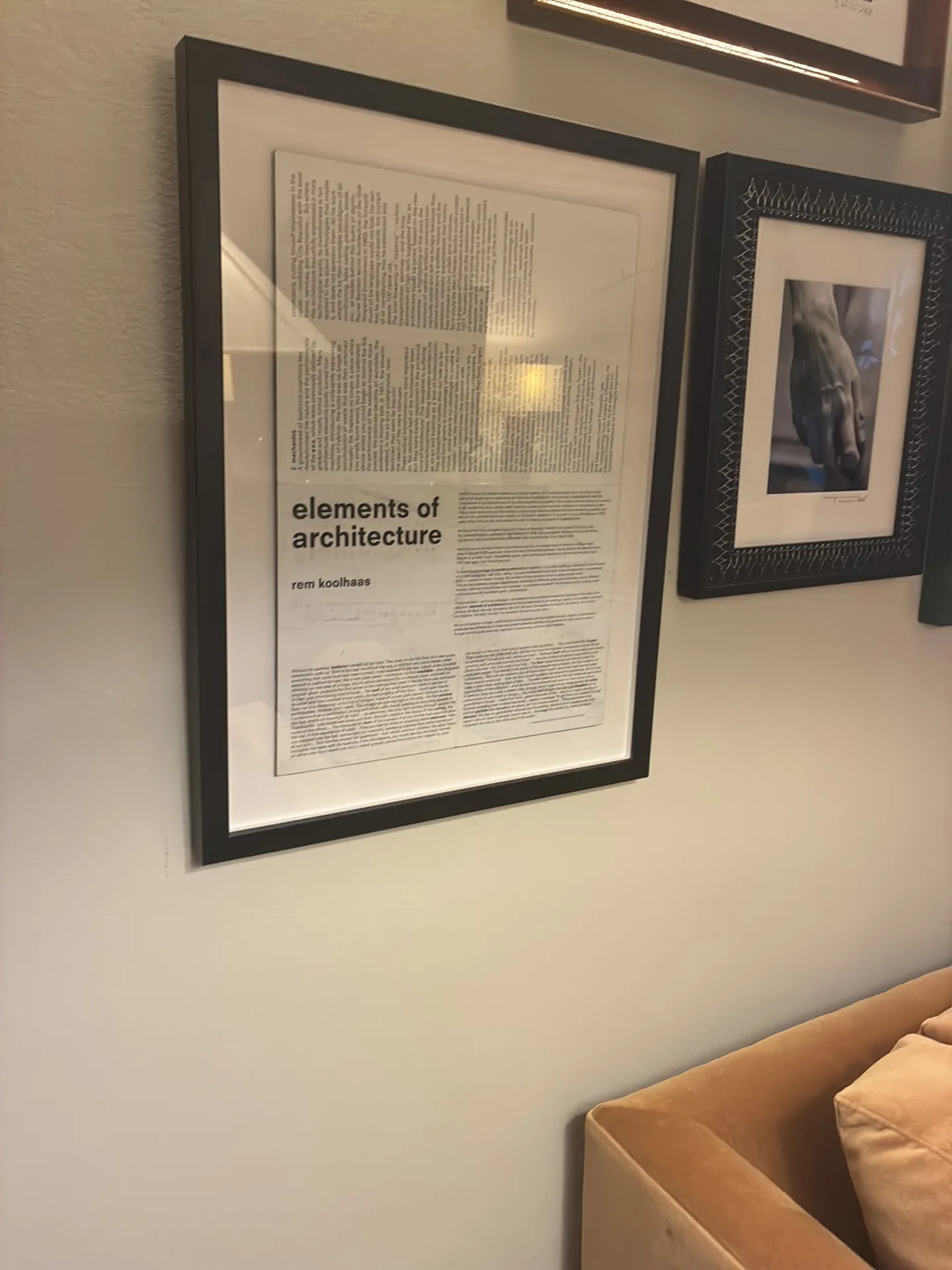 A large black-framed architecture text print beside another framed print above a sofa.