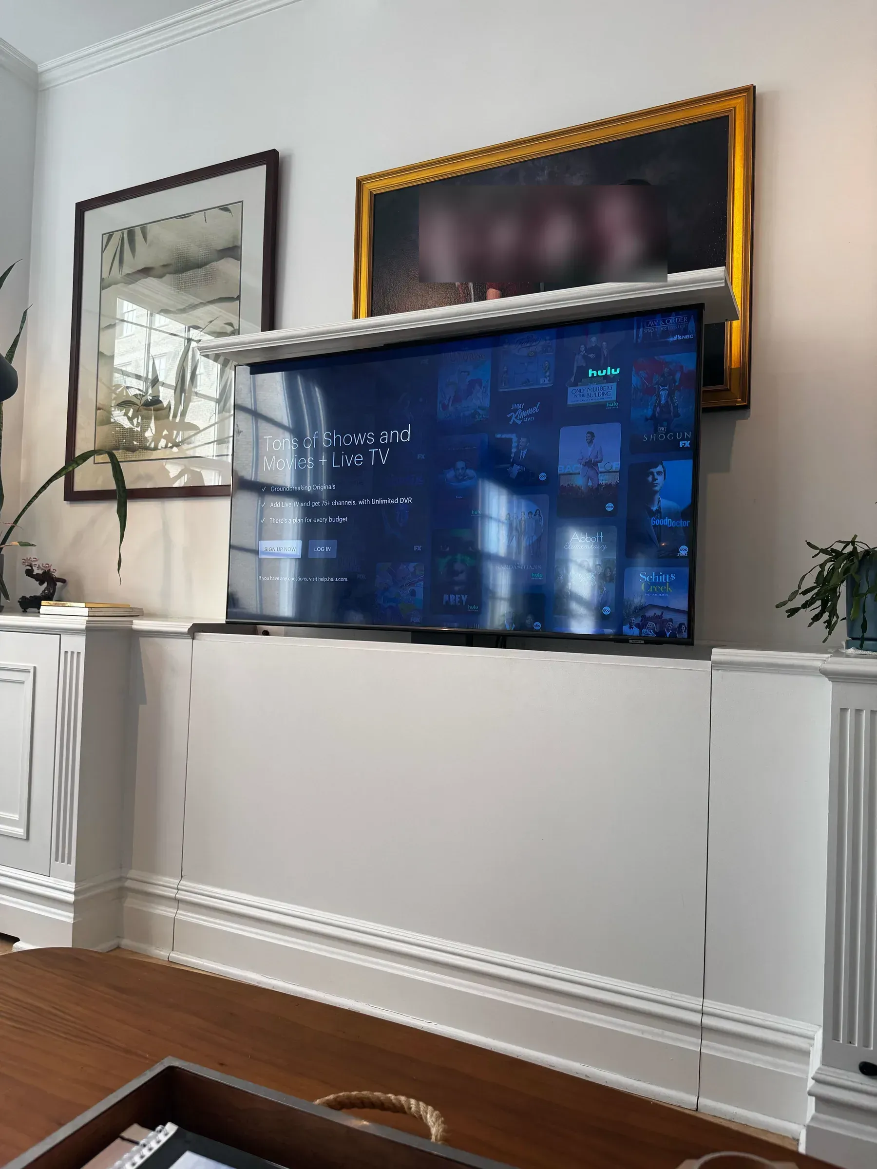 A closer view of the TV raised above its cabinet, displaying a streaming service home screen below the family portrait.