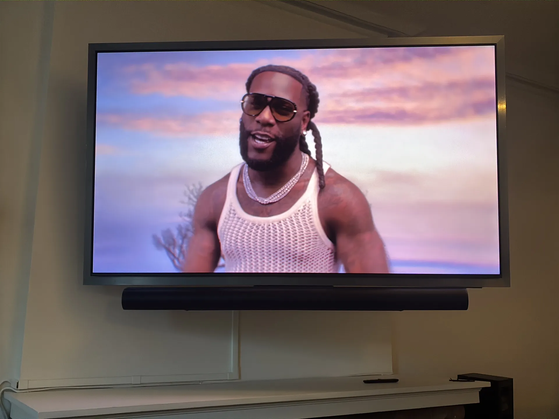 A wall-mounted TV with a soundbar mounted below it and a cord cover on the wall.