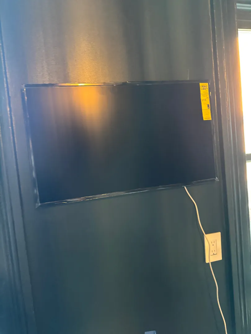 A TV mounted on a dark wood-paneled wall, its energy-guide sticker still attached.