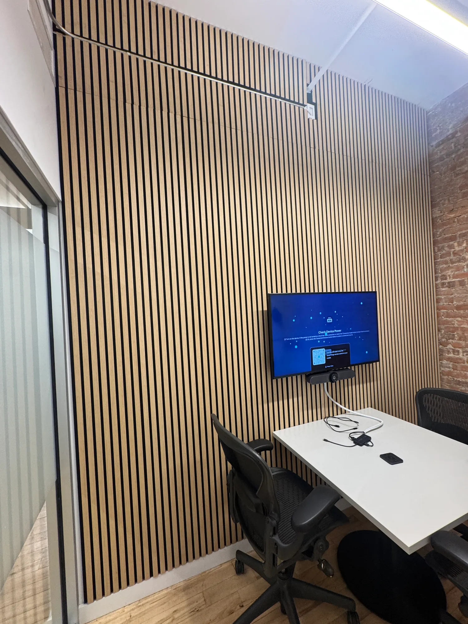 A small room with wood panels floor to ceiling and a TV mounted above a small table.