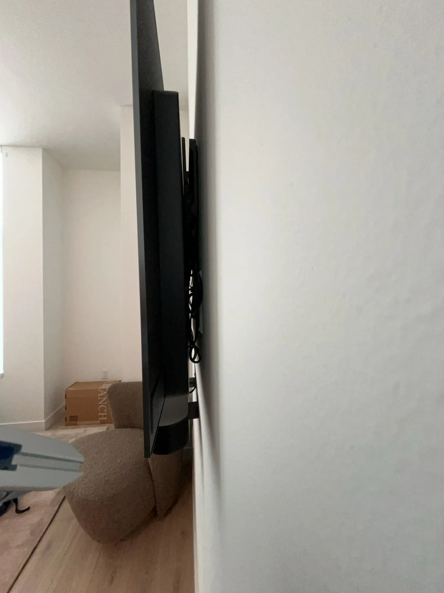 A side view of a TV sitting flush against the wall with cables tucked behind it.