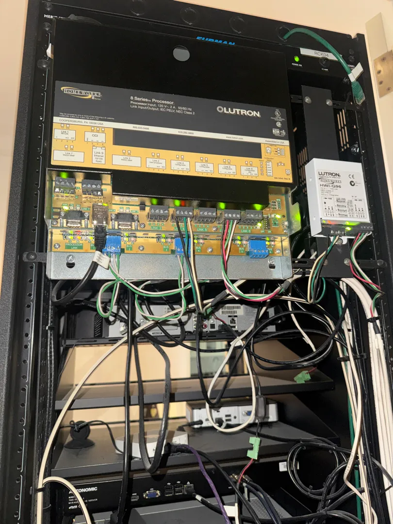 A Lutron home lighting-control processor and its wiring, mounted in the same equipment rack as the audio gear.