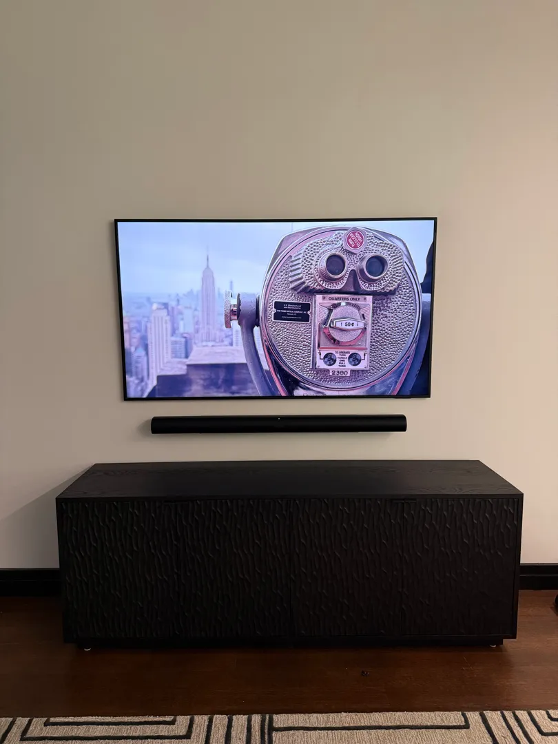 A wider view of the mounted TV, soundbar and cabinet in the living room.