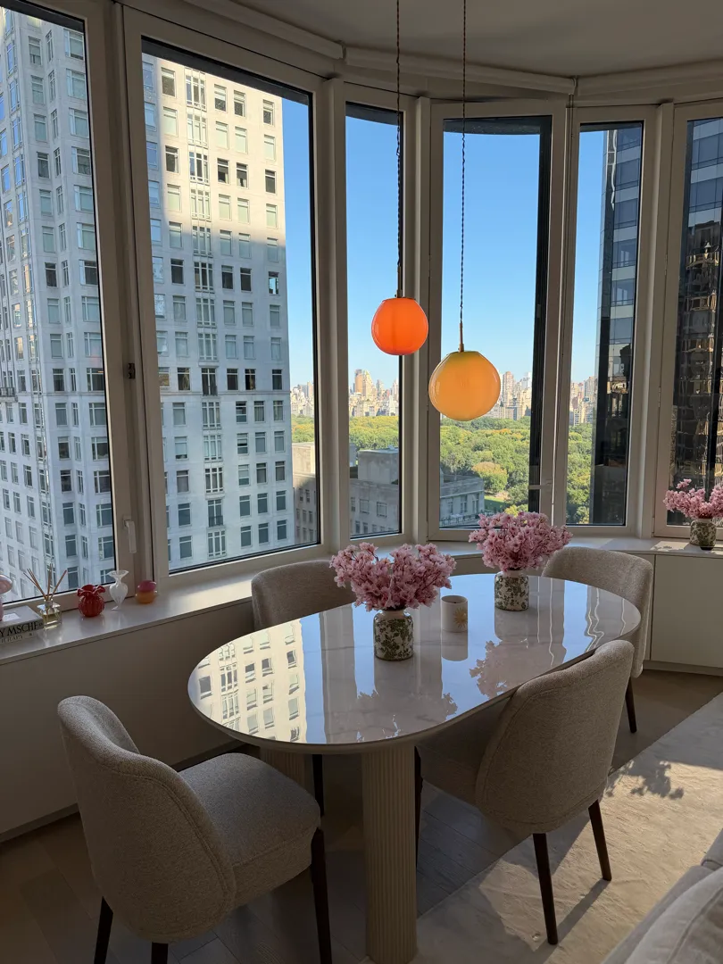 Two glass globe pendants hanging over the oval dining table in front of the curved windows.
