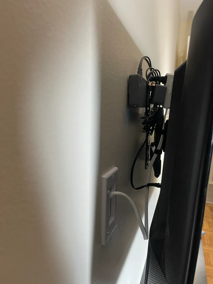The back of a wall-mounted TV showing tidy cables and a wall outlet.