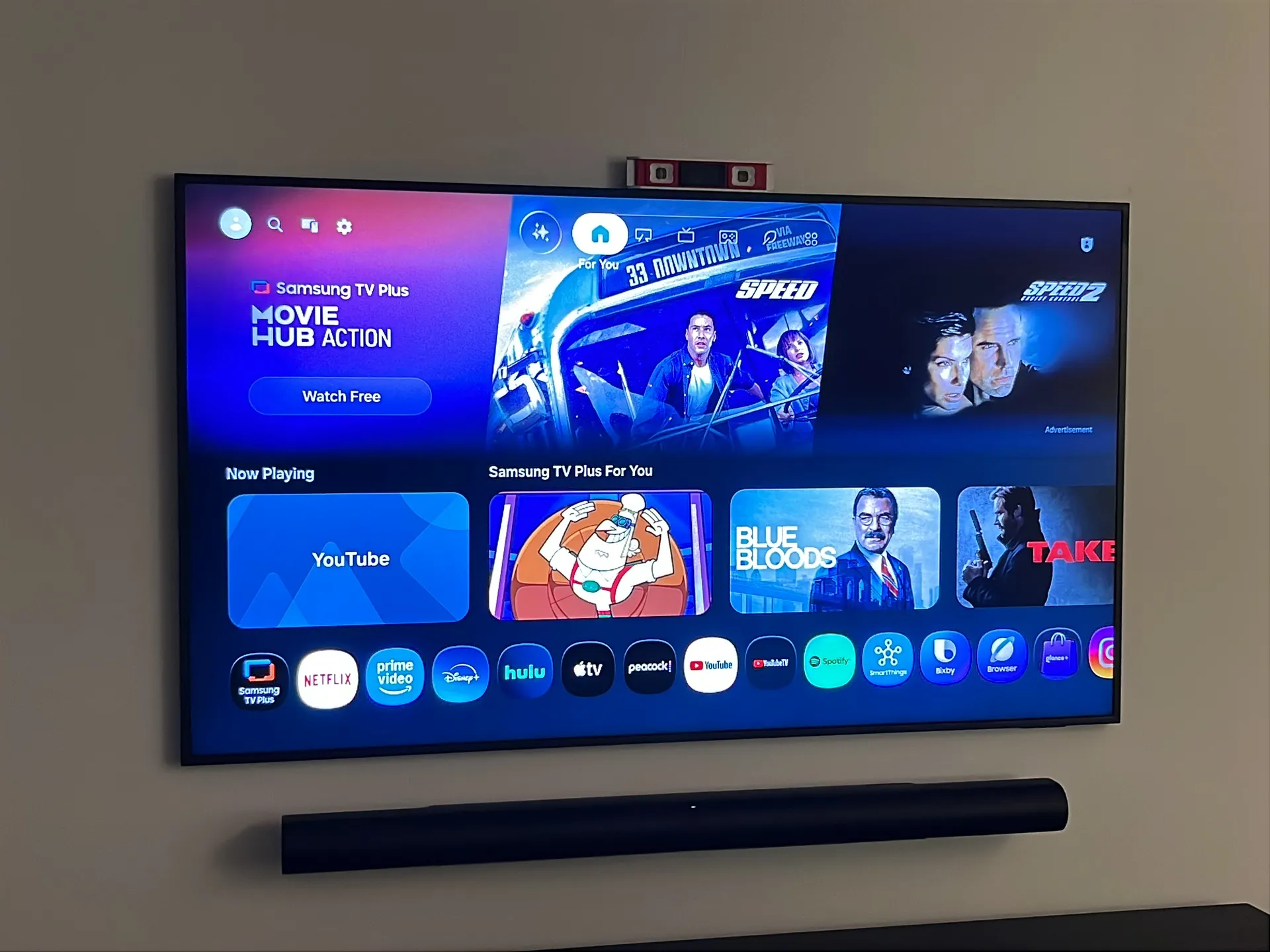 The mounted TV and soundbar with a level still resting on top of the screen.