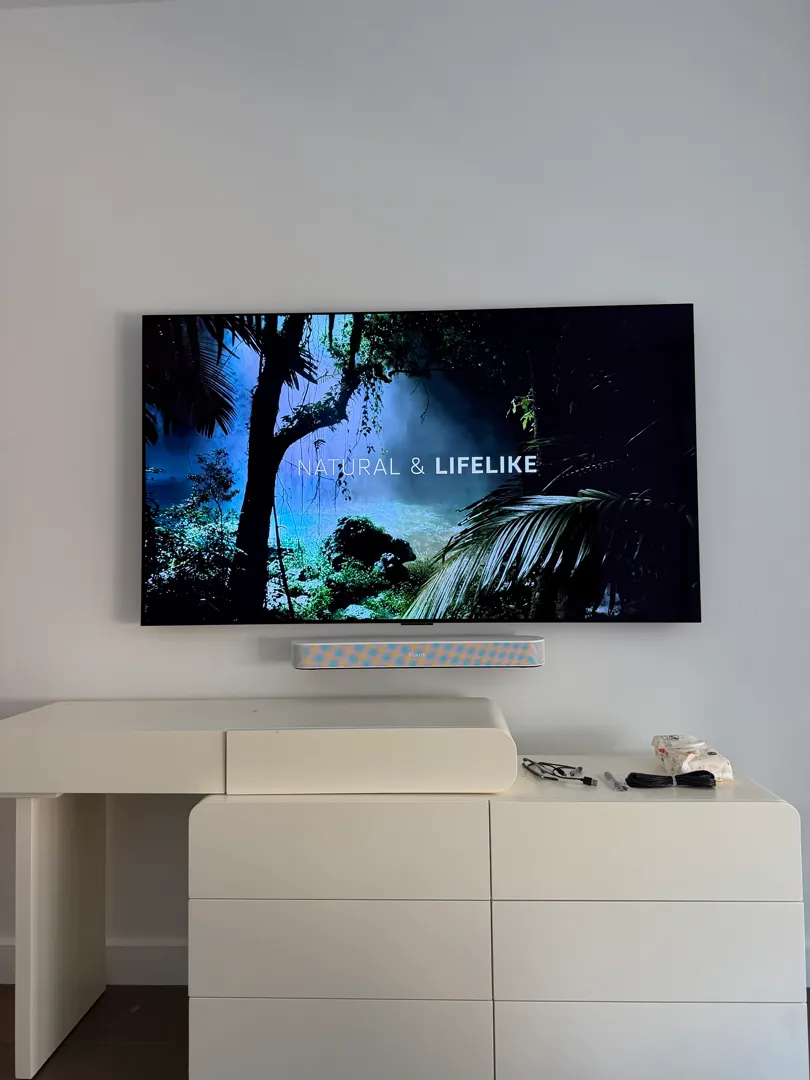 The TV's on-screen settings menu showing Sound Out set to HDMI ARC, with the LG webOS home screen visible behind it.