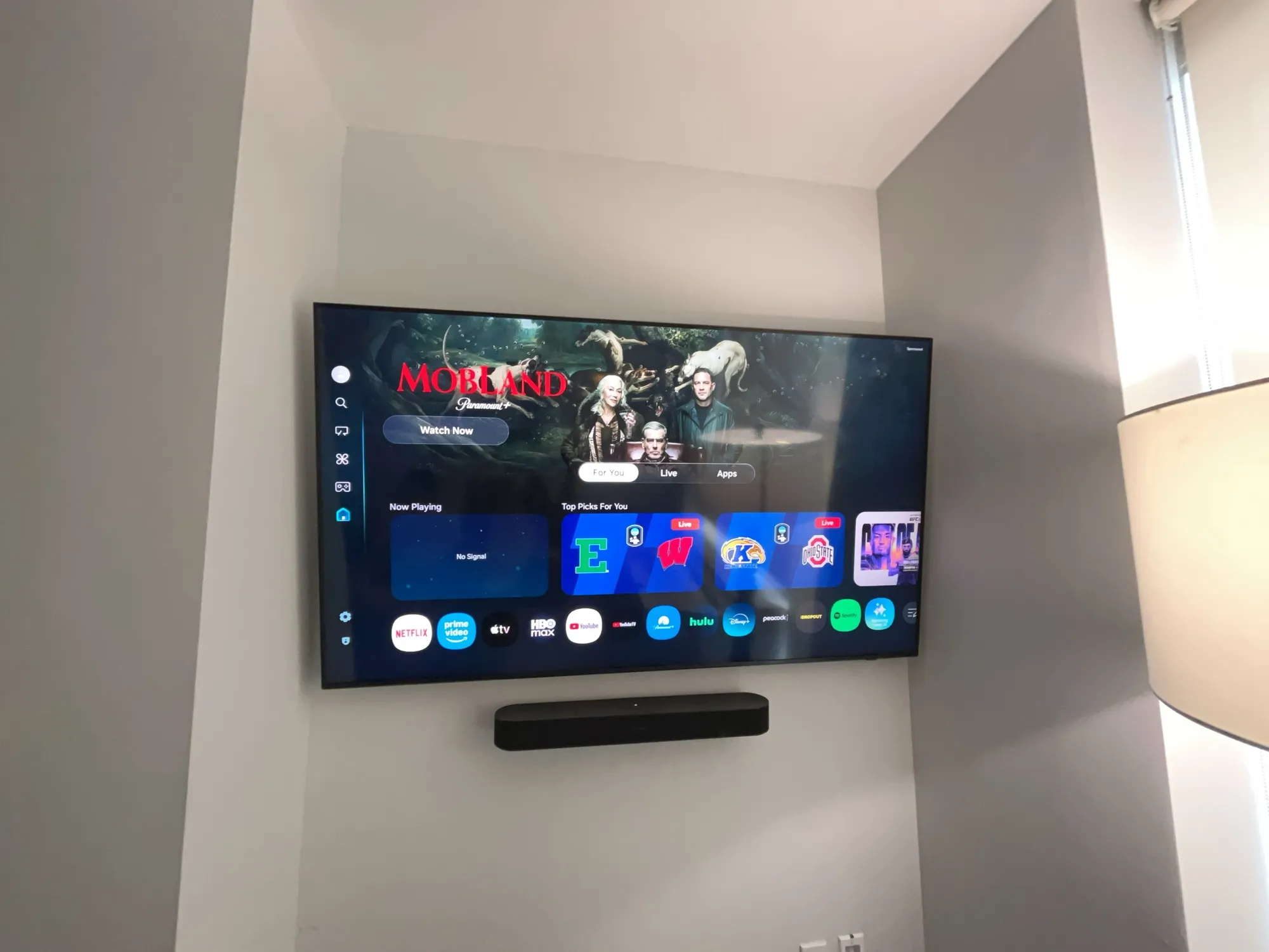 A wall-mounted TV in a different room showing a streaming home screen, not matching this job's wall.