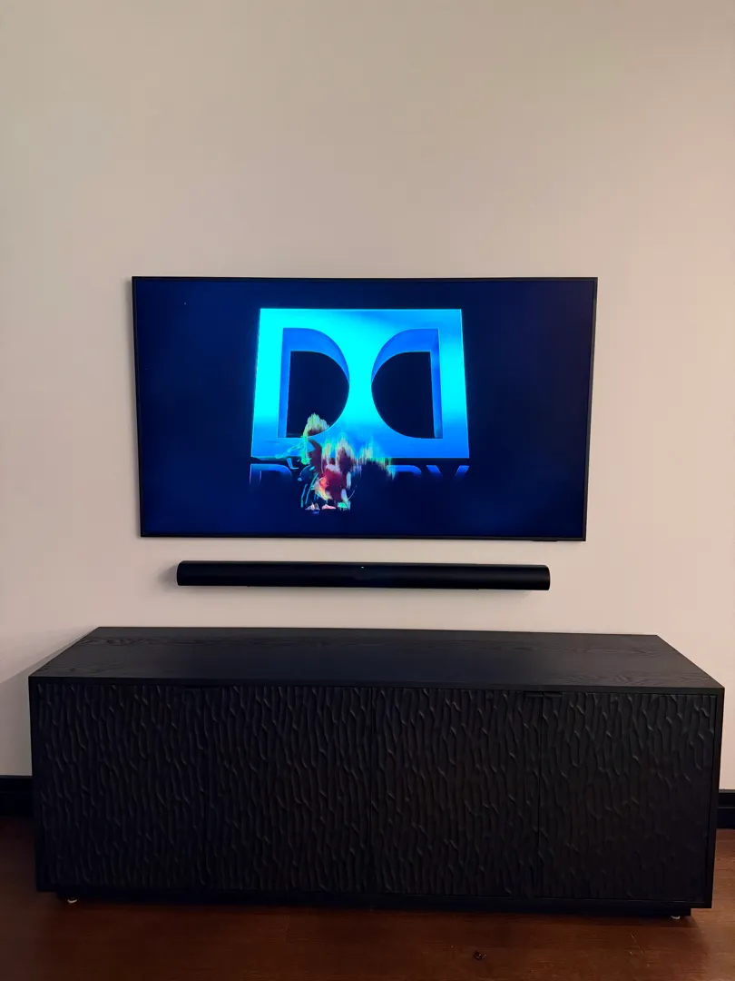 The TV, soundbar and black cabinet viewed straight on, with the wall clear of cables.