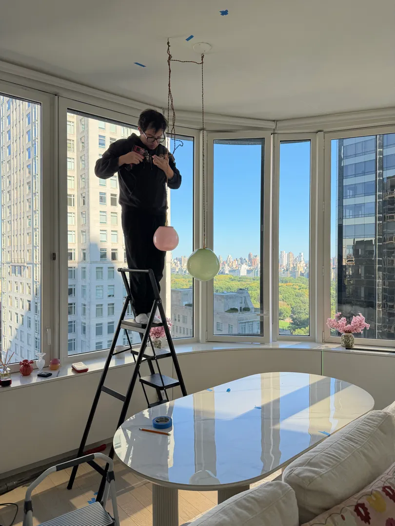 A technician on a ladder hanging the pendants from the ceiling over the oval dining table.