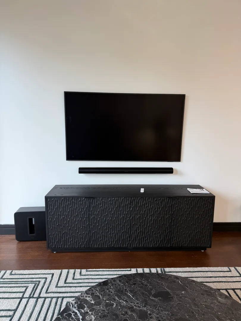 wall-mounted TV and soundbar above the console, shown from a slightly different angle with the subwoofer on the floor.