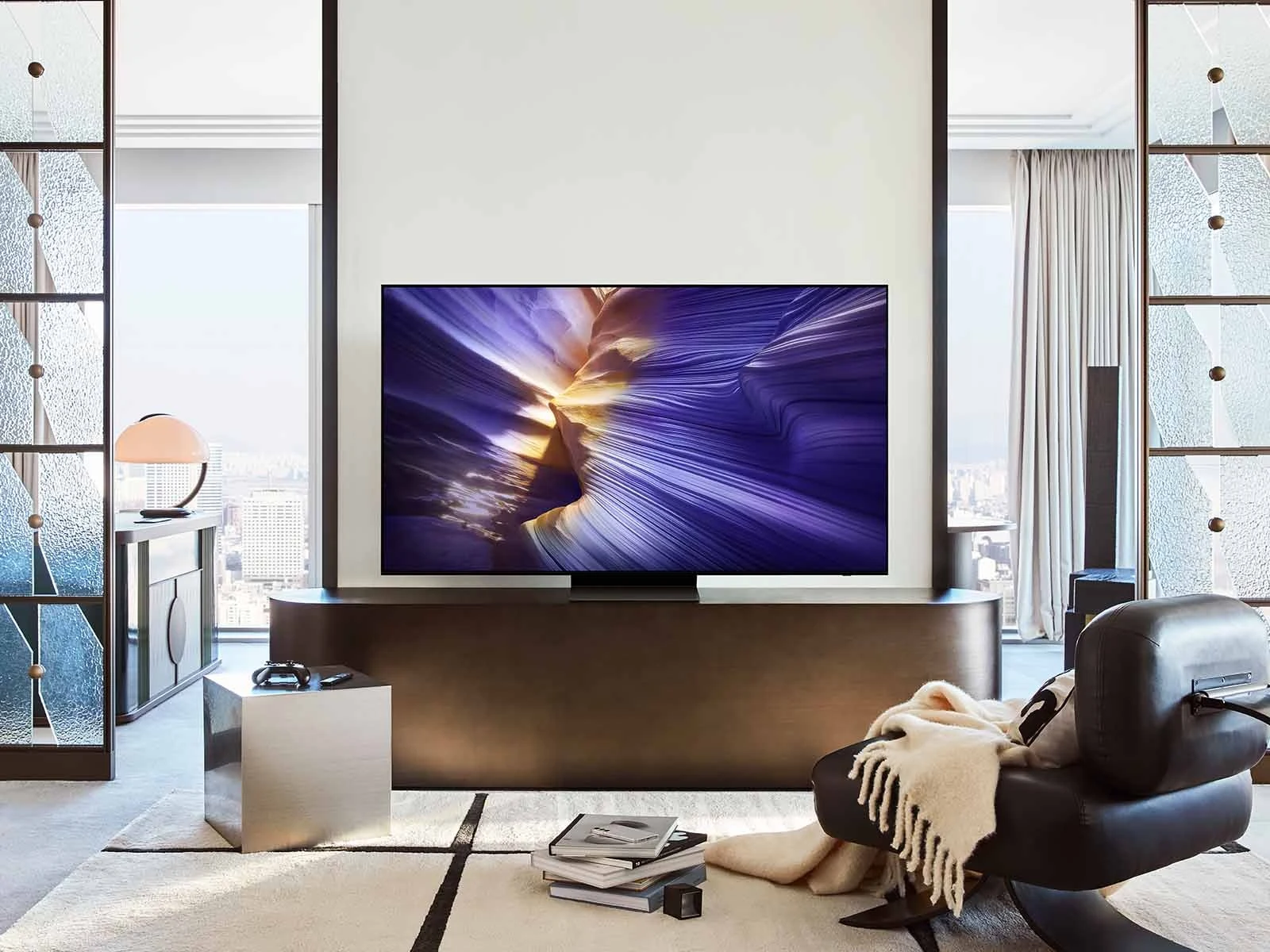Samsung OLED S90F mounted between two glass doors in a modern high-rise apartment with a city skyline view