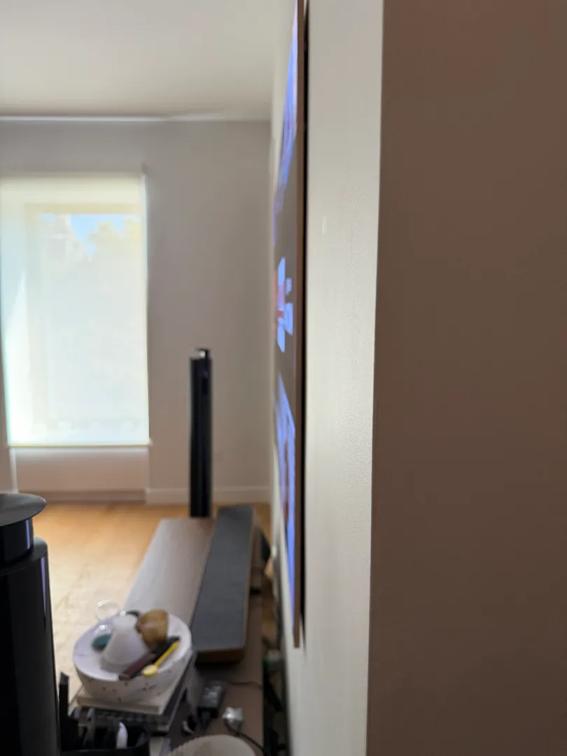 Side view of the LG W6 wallpaper TV beside a window, showing how slim it sits on the wall.