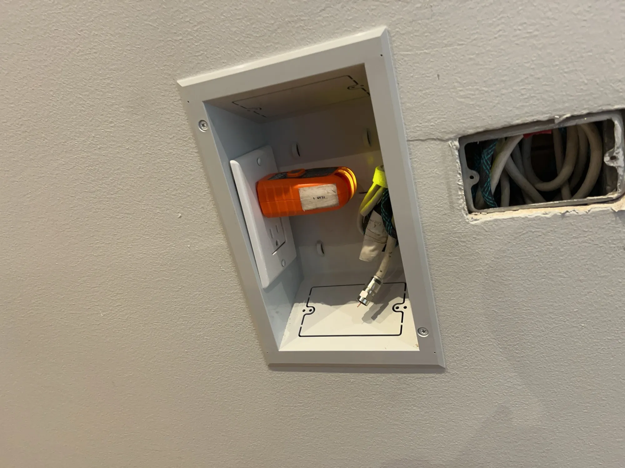 An open recessed outlet box with power and coaxial connections mid-install.