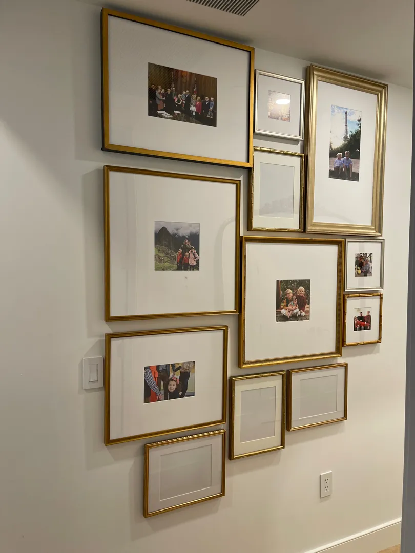 Finished gallery wall of gold and silver picture frames arranged in a tight group.