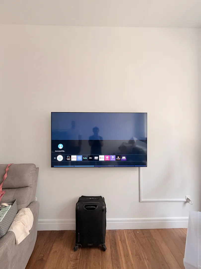 A wall-mounted TV shows an app menu above the living-room seating.