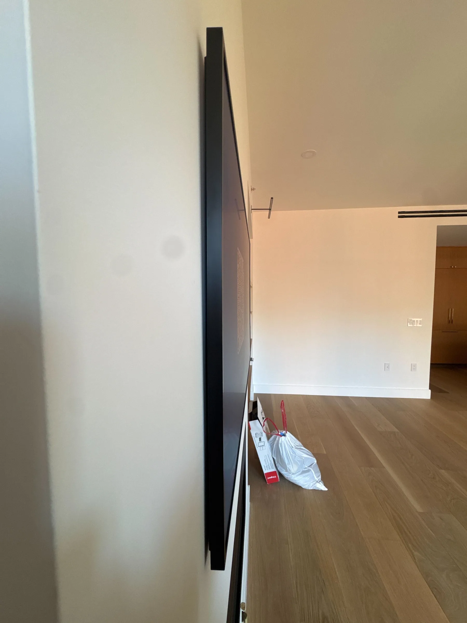 A Frame TV mounted flat on the wall of a new-construction apartment with a vaulted ceiling.
