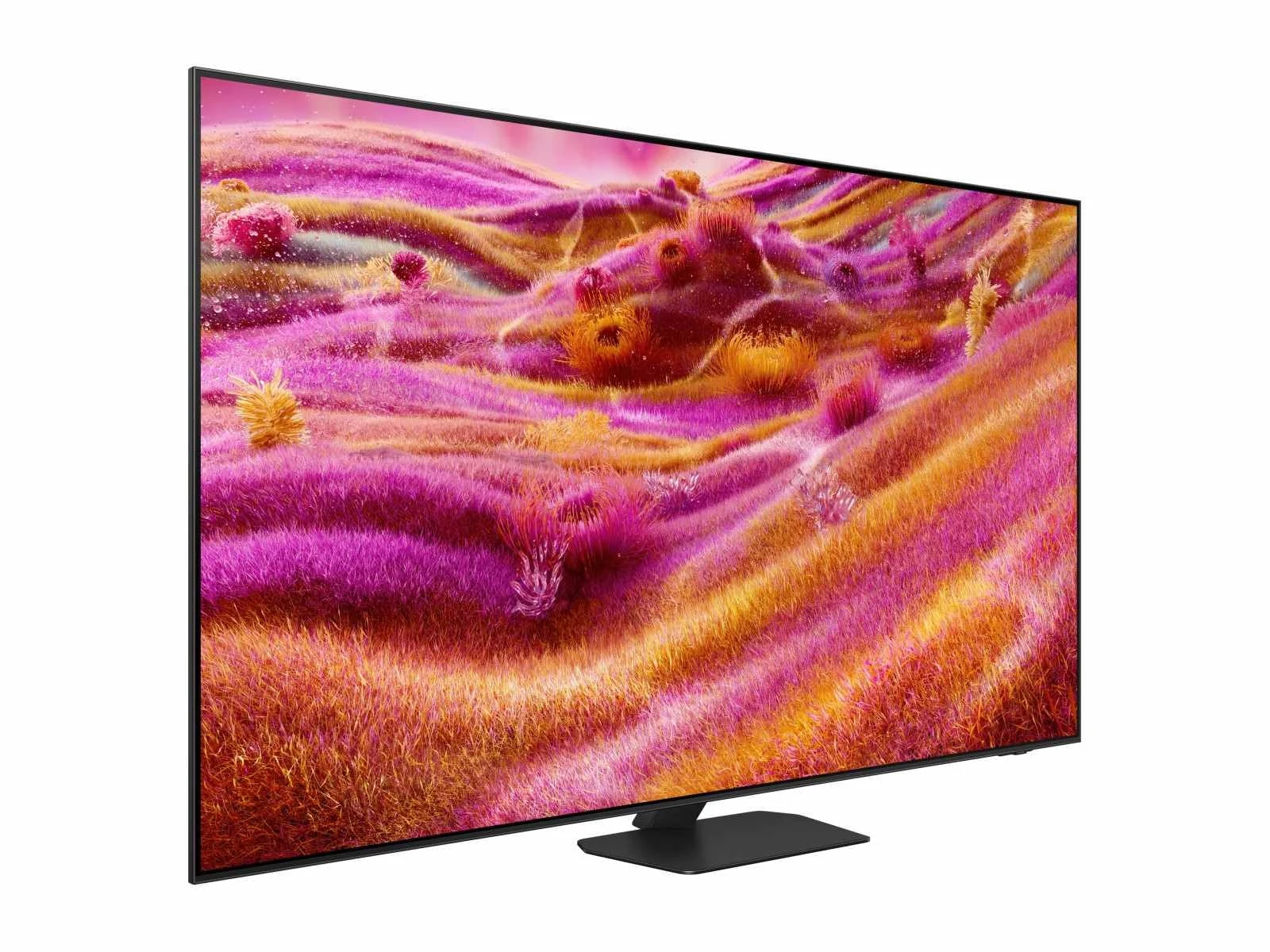 Three-quarter angle view of the QN90F, showing its thin bezel and center pedestal stand against a magenta and gold grass-like screen image.