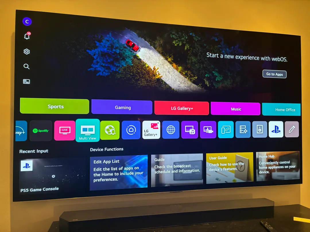 A wall-mounted TV showing its home screen from an angle above a soundbar.