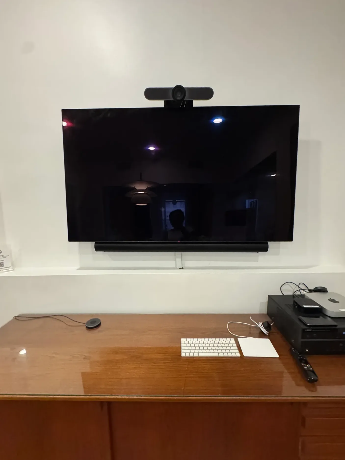 The office TV as it was before the visit, with a video conference bar on top and a soundbar below, above a wooden credenza.