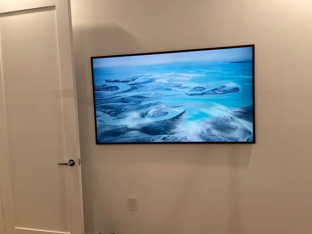 Second Frame TV mounted on a white hallway wall beside a door.