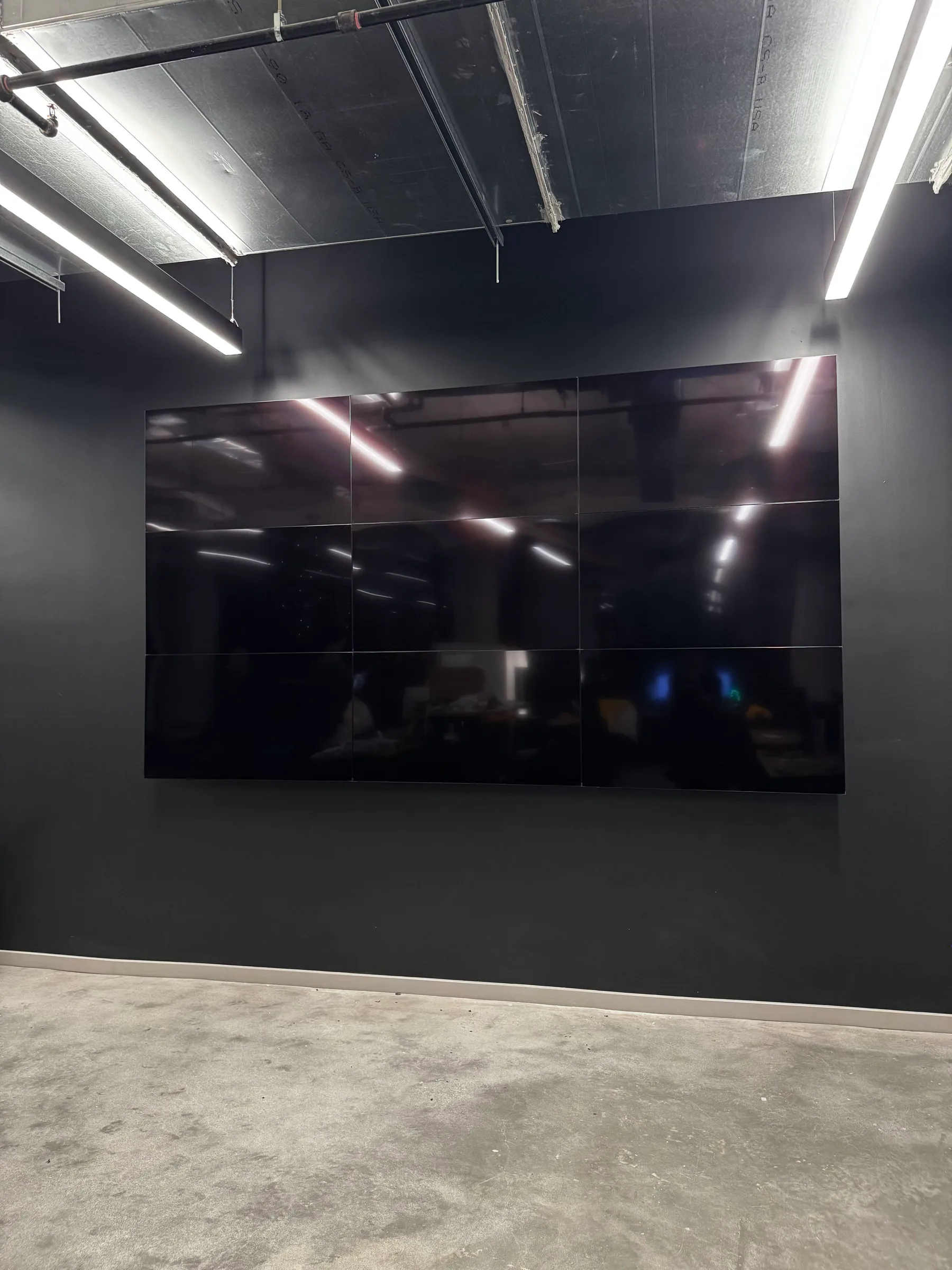 Nine lit Video Wall screens on a black office feature wall