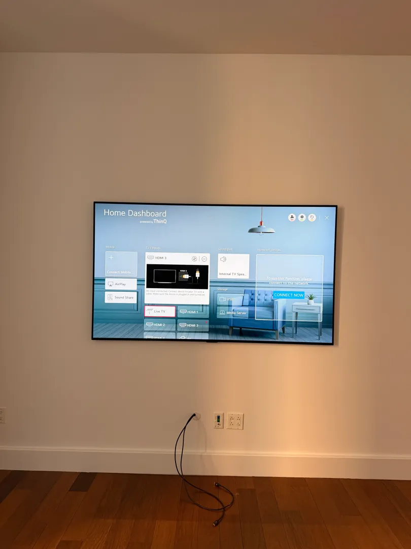 A mounted TV shows its home dashboard on the finished wall.