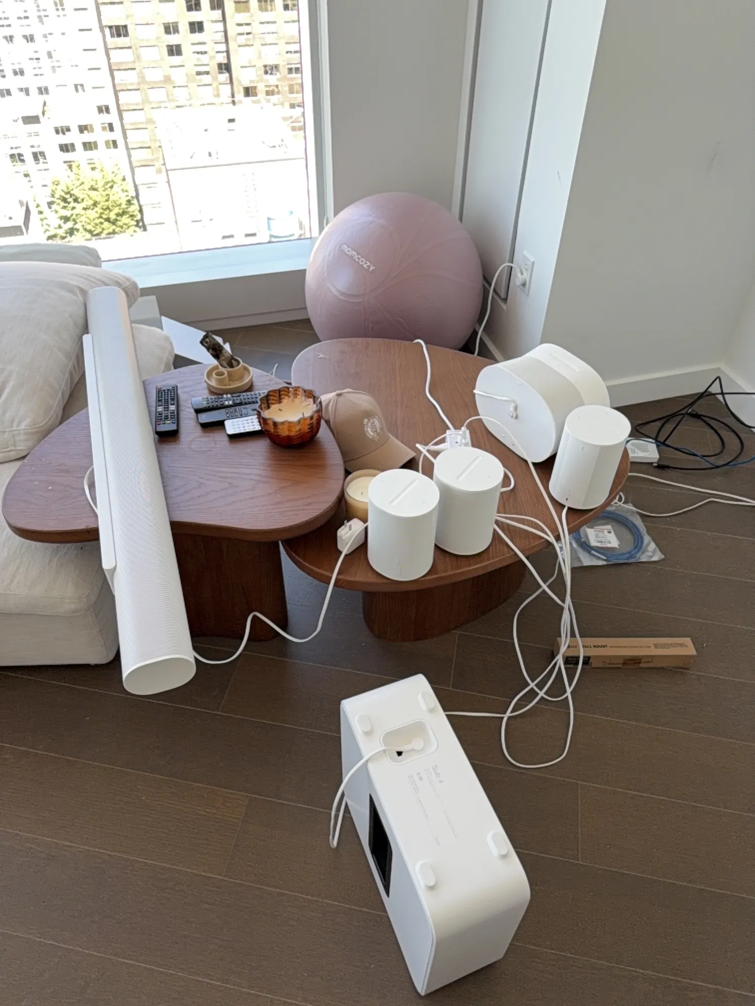 Sonos equipment, a subwoofer, speakers, and a soundbar box, staged and unboxed on the living room coffee table.