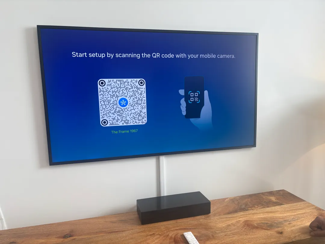 A wall-mounted TV above a black box on a wooden console, with a white cord cover on the wall.