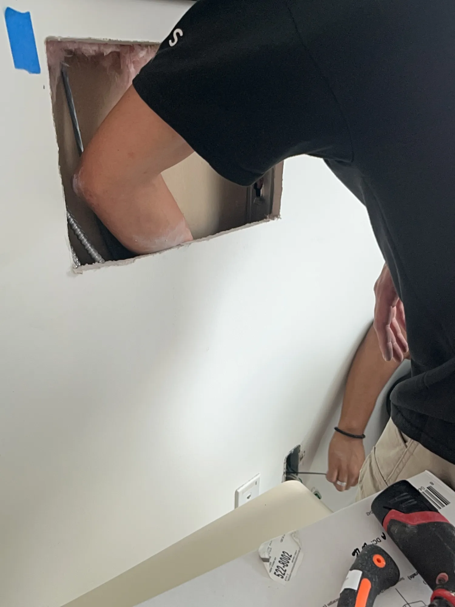 A closer view of the same cut-open wall cavity and outlet work, with a second cut visible above.