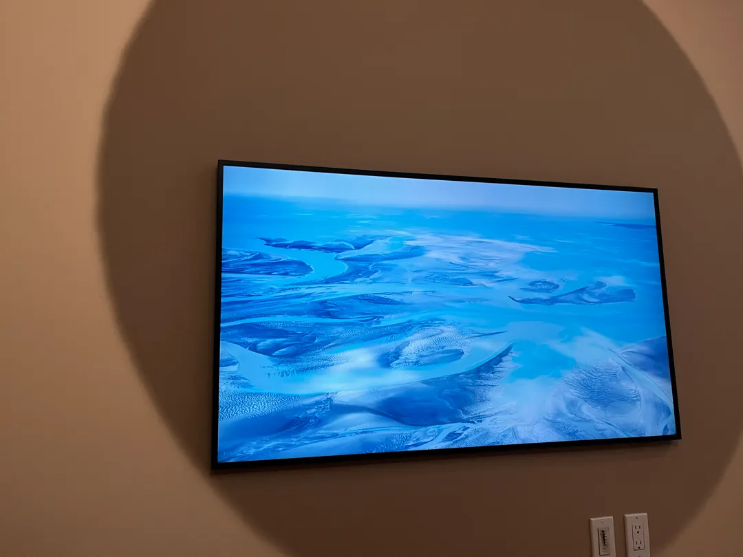 The finished TV mounted flush to the wall, displaying an aerial landscape image in Art Mode.