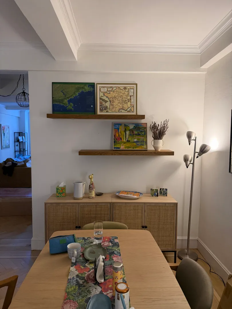 Floating shelves with framed art above a sideboard.