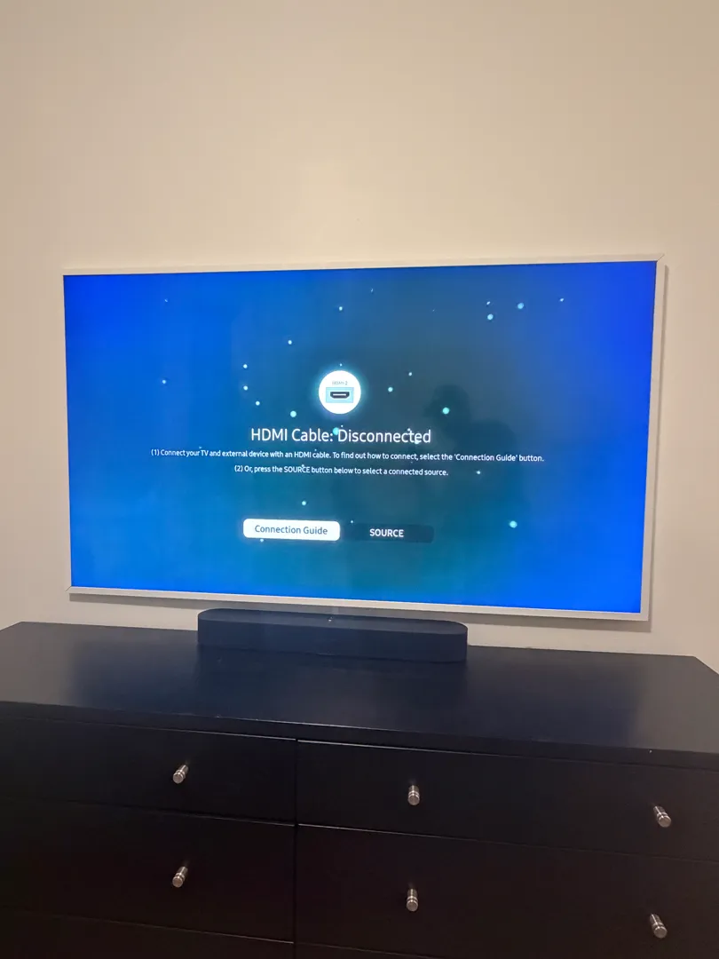 The Frame TV flush-mounted on the wall, powered on, with a soundbar on the dresser below.