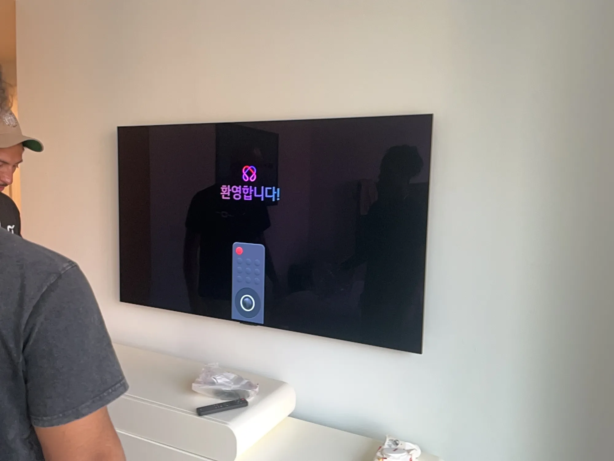 The bedroom TV mounted and powered on, showing an LG welcome screen with an on-screen remote graphic.
