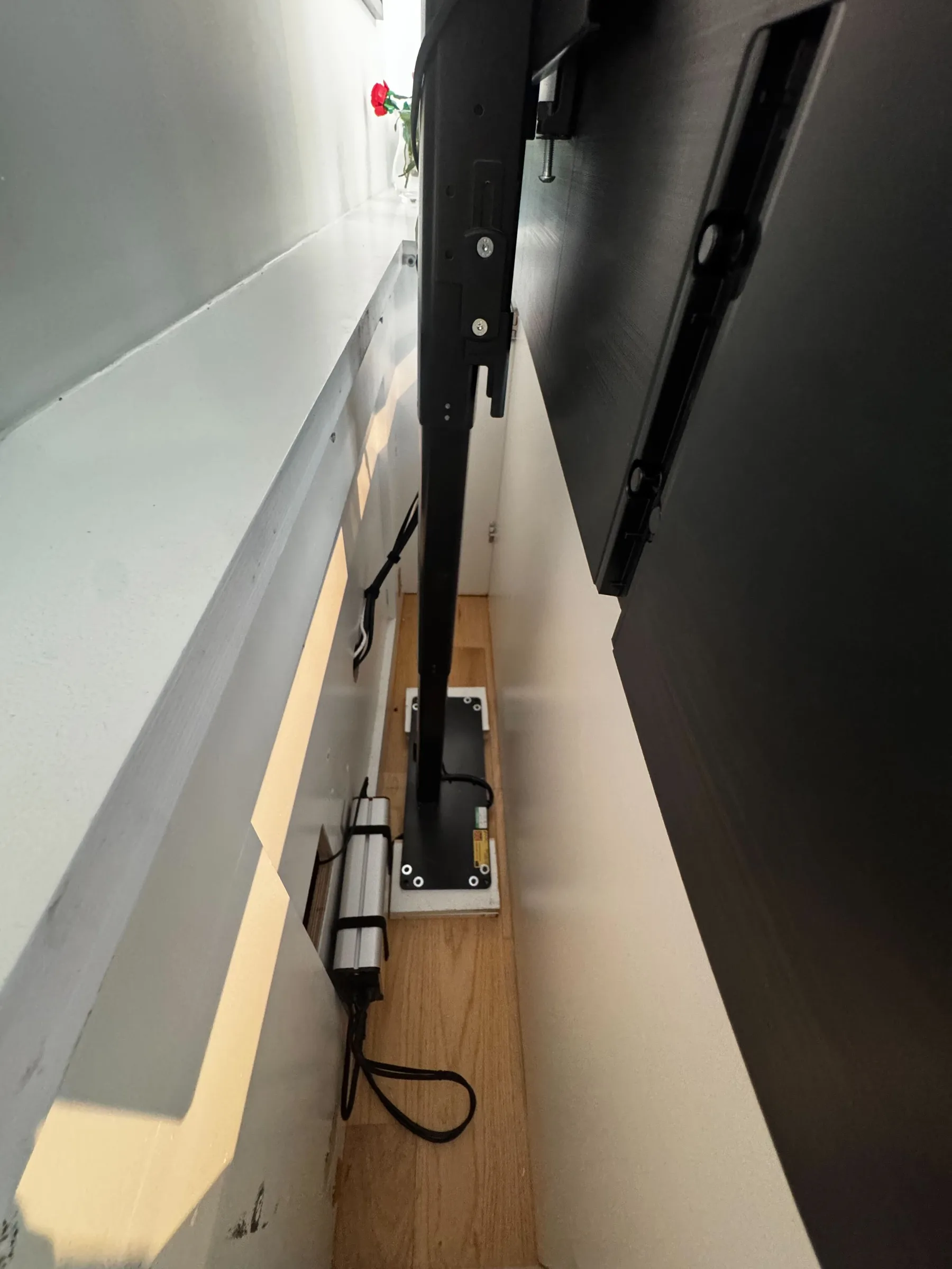 A view inside the cabinet showing the motorized lift mechanism and mounting bracket that raises the TV.