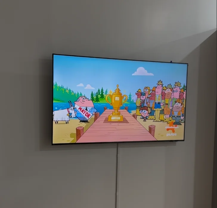 TV mounted on wall showing cartoon content, kids room